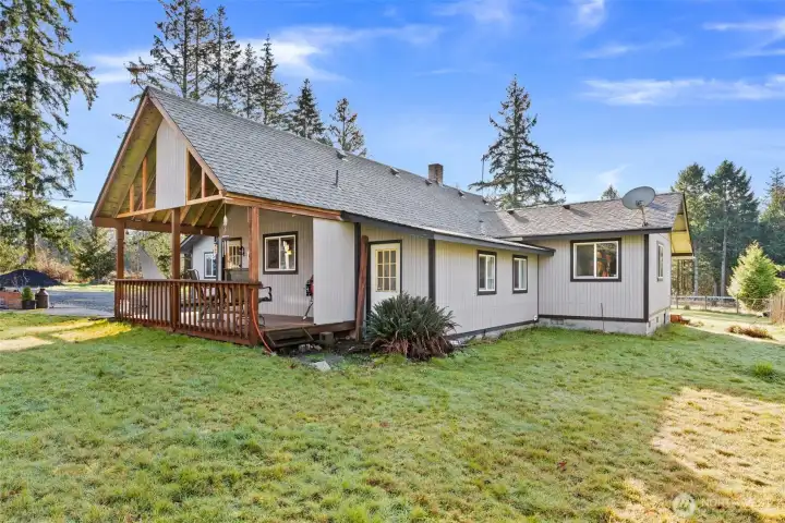 Covered rear deck with spacious backyard beyond.