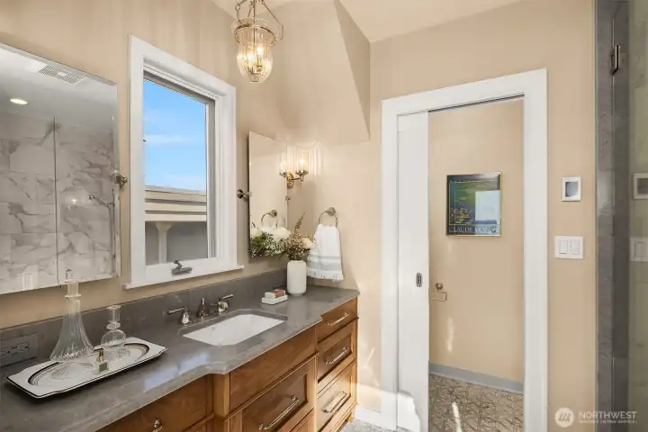 Spa like primary bathroom with marble floors, quartz counters, gorgeous hardwood vanity and radiant heat floors.
