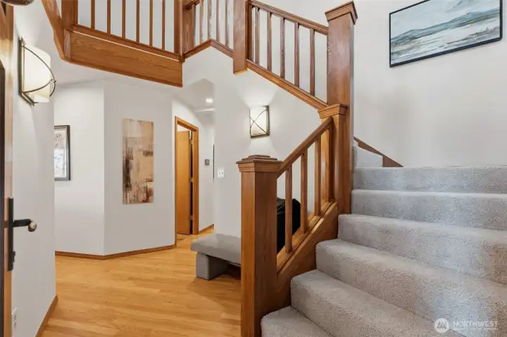Welcoming foyer featuring rich wood railings, hardwood floors, and soaring ceilings.