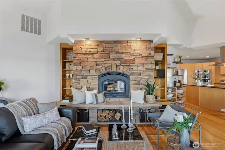 Inviting living area featuring hardwood floors and a striking stone fireplace surround.