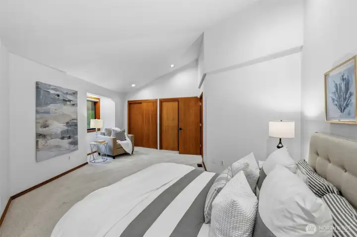 Spacious bedroom featuring vaulted ceilings, soft carpeting, and flexible sitting area.
