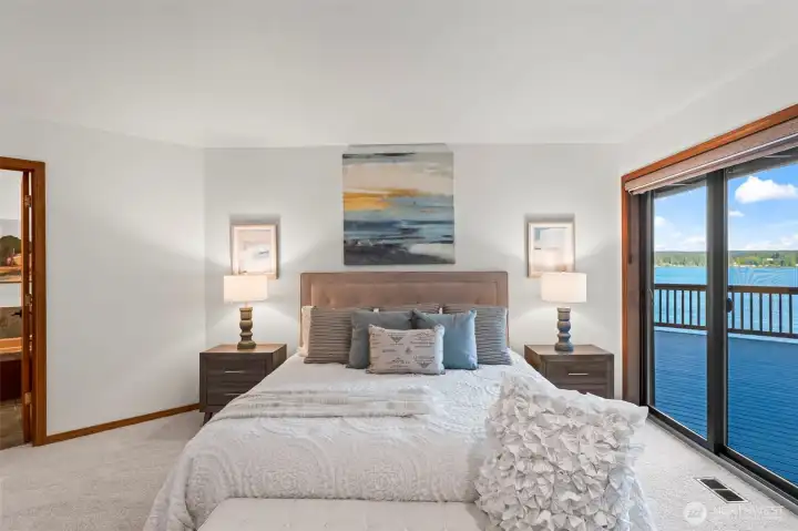 Inviting primary bedroom retreat featuring large sliding doors overlooking the water.