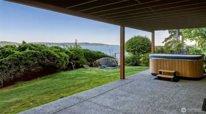 Covered patio area with hot tub and surrounding water views.