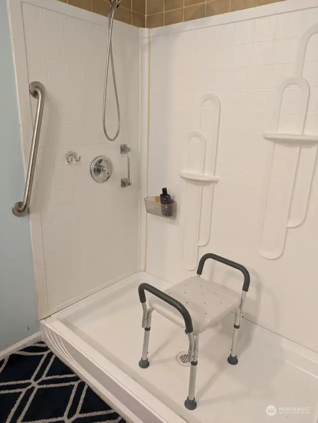LOW RISE SHOWER. Walk-in shower with hand rails for comfortable accessibility and safety.