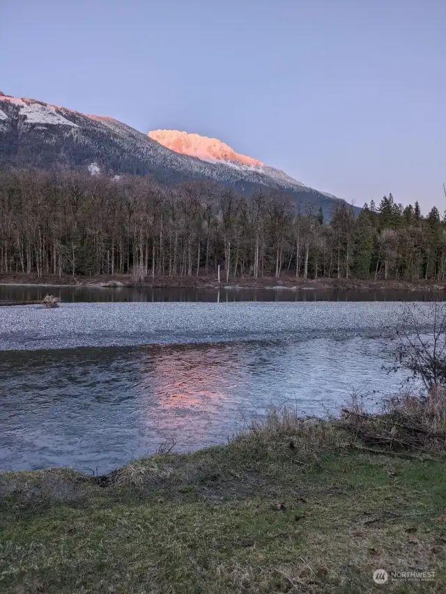 BACKYARD VIEW. Gorgeous alpenglow light. Snow level on 5,500 foot Sauk usually seen in winter. spring and fall.  House at 215 above sea level captures the warm air flowing up from Skagit Valley tulip fields, to come up to this banana belt.