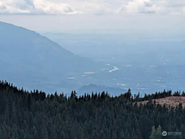 VIEW FROM MT. SAUK. Entire Skagit valley narrows to Mt Sauk and our river-front home. Narrowing valley captures cool rain in spring and warm air in winter.  Slow the drift of climate change, as you are in naturally watered area. Wonderful for gardening.