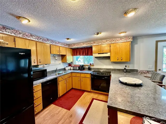 The kitchen features laminate floor, eating bar, lots of cabinet, breakfast nook and view of the back deck and yard from the kitchen window.