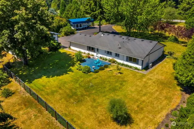 Rear view of the home and yard area. The additional property is beyond the fence in this photo.