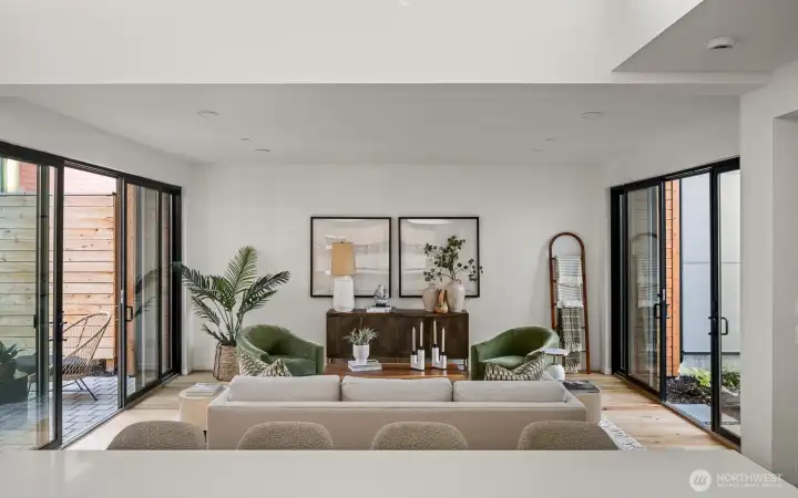 This spacious living room is enhanced by expansive sliding glass doors and windows, seamlessly blending indoor and outdoor living while flooding the space with abundant natural light.