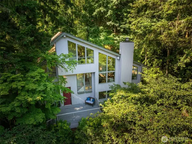 Welcome to a home where striking architectural angles and walls of glass create a bold silhouette—perfectly nestled into the tranquility of its wooded surroundings.