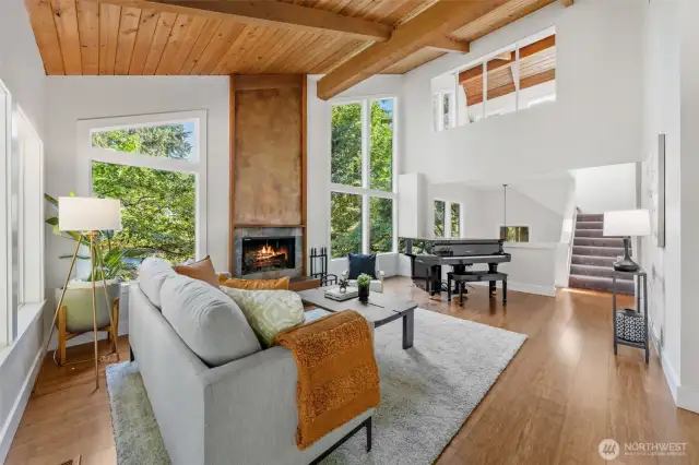 Soaring ceilings with exposed beams and a warm wood finish set the tone in this light-filled living room,  complete with a wood burning fireplace and treetop views.