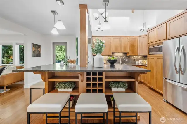 This generous kitchen island offers ample prep space, casual seating, and smart built-in storage—including wine cubbies and open shelving to keep essentials within easy reach.