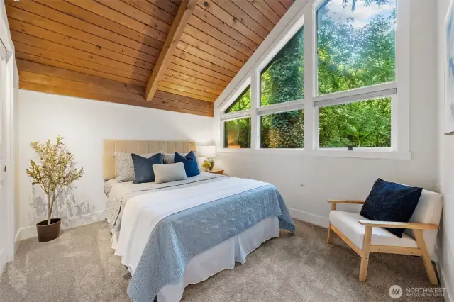Bedroom Two features soaring ceilings, lush views through oversized windows, and generous space for rest or reading.
