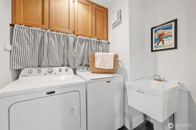 The dedicated laundry room off the kitchen includes upper cabinetry and a utility sink—designed for both function and efficiency.