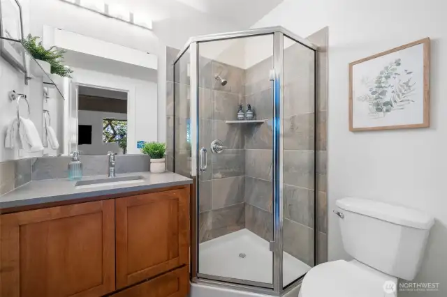 Conveniently located off the den is a bathroom with a glass-enclosed shower and sleek finishes—perfect for guests or post-workout refreshes.