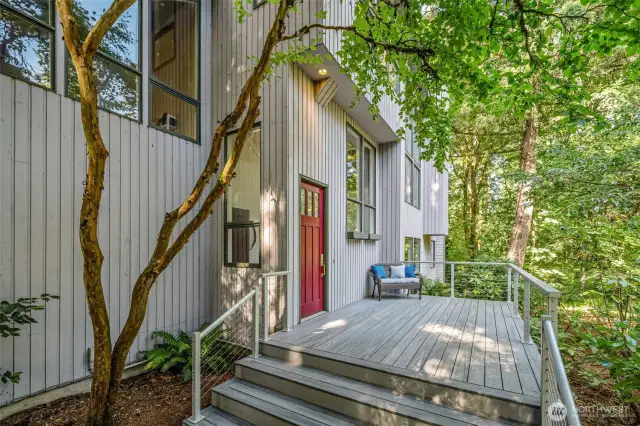 Inviting front deck provides a quiet spot to take in the surrounding greenery, framed by timeless architectural details and natural charm.