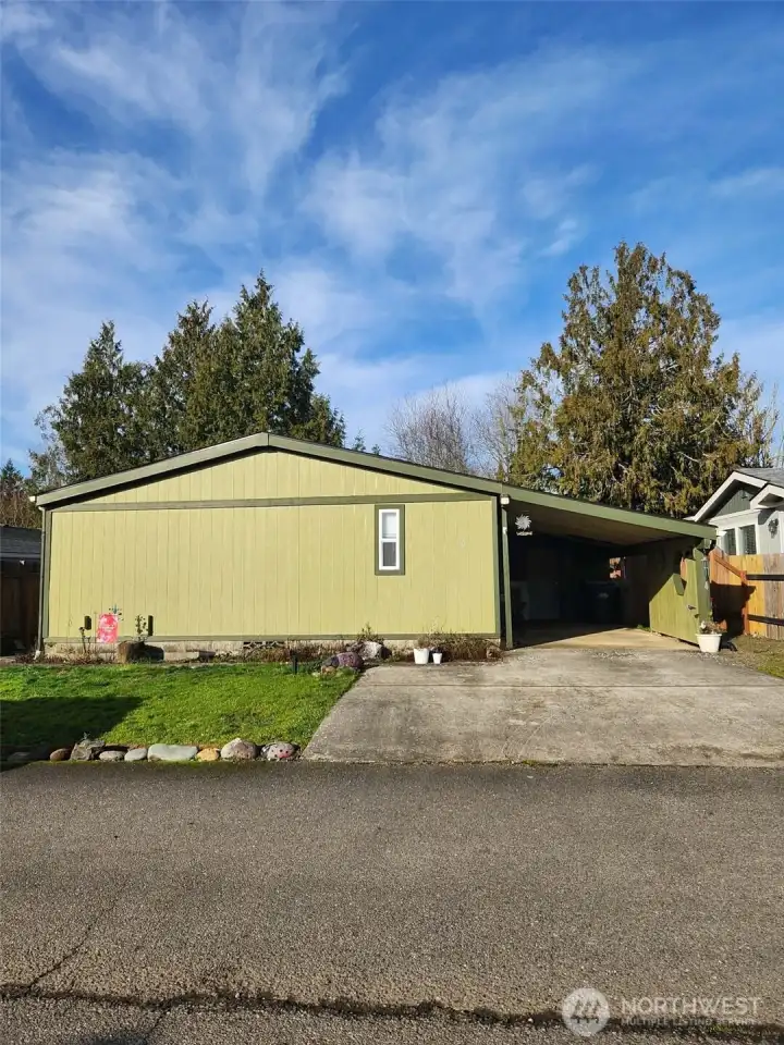 End of the home faces the road. Covered carport to keep you comfortable! Side door allows for easy access to home. Spacious storage at the end of the carport. Additional parking in the driveway.