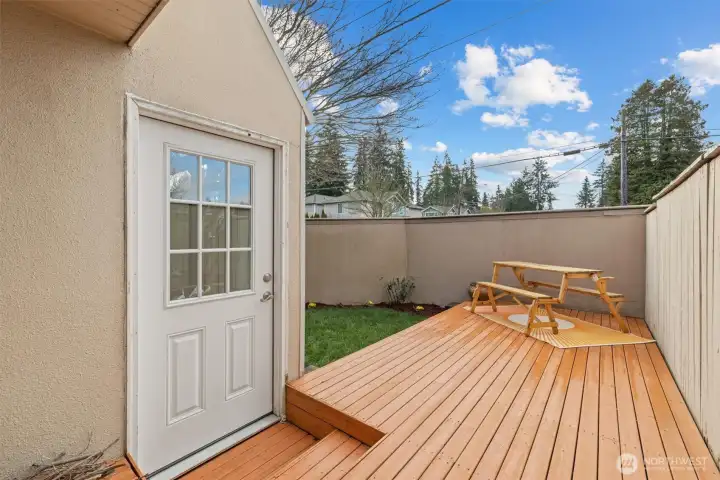 The deck leads to grassy space and garden area.