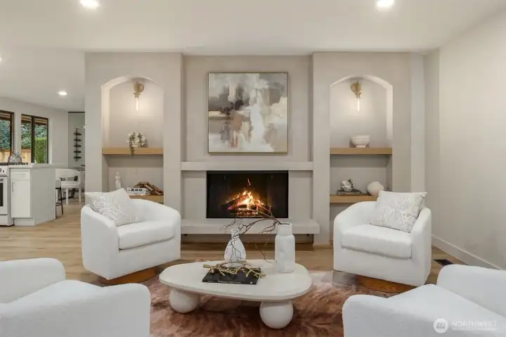 Open concept living room provides woodburning fireplace, built-in shelves and modern lighting.