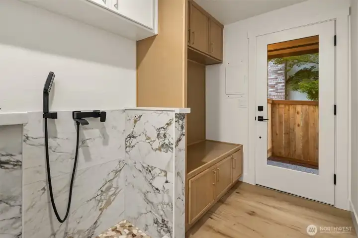 Mud room between garage and kitchen offers Doggy Shower, Coat & Shoe bench and access to sideyard.