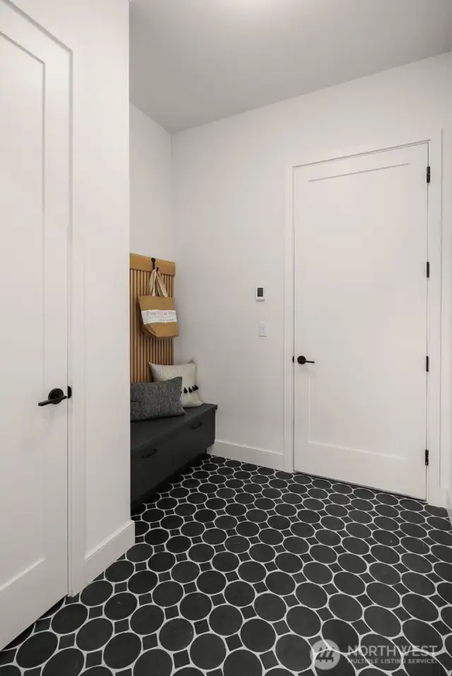 Spacious mud room with amble built-in storage, heated floors and a coat closet.