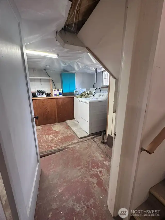 Bottom of steps looking into laundry and one storage area.