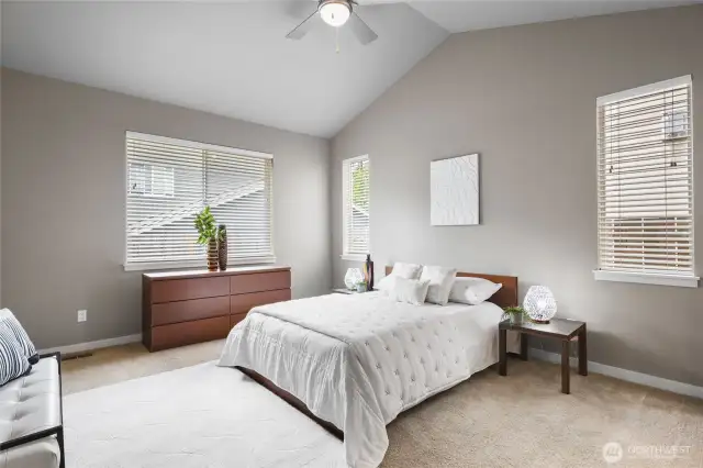 Spacious and serene primary suite with abundant natural light, plush flooring, and an ideal retreat for rest and relaxation.