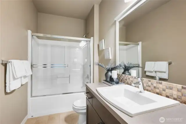 Updated guest bathroom with sleak fixtures, full-size tub, and tasteful design.