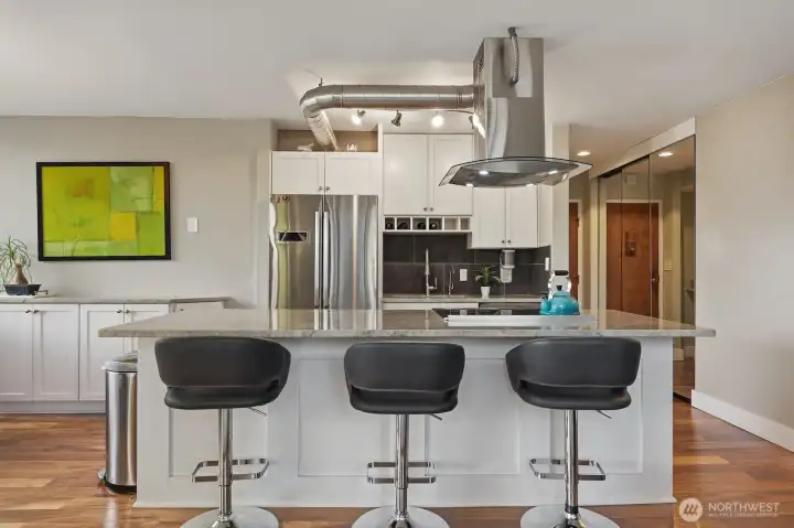 Outfitted with quartzite counters, stainless appliances, stylish cabinets, and an island with bar seats - perfect for hosting.