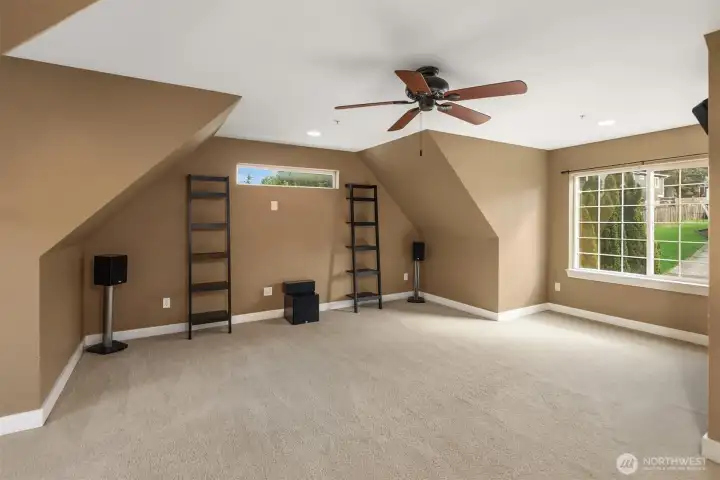 Bonus room on upper level  with built-in speakers, storage cabinetry, ceiling fan, and an adjacent laundry area.