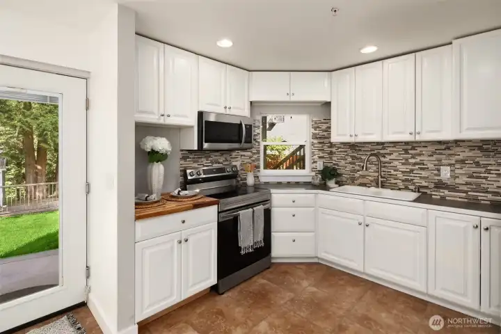 Second kitchen in the lower level - featuring tile flooring, LG stainless steel refrigerator, Samsung microwave, built-in oven,  and an eating area.