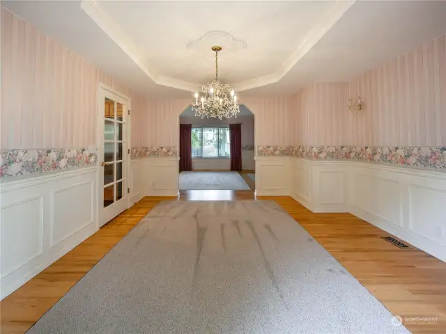 Formal Dining area with coffered ceilings and elegant chandelier. Wainsoting throught these 2 beautiful rooms.