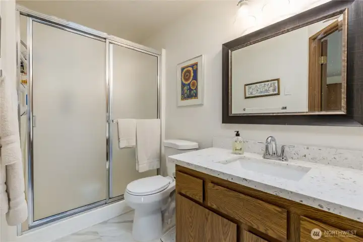 Primary bathroom with updated flooring and quartz-topped vanity.