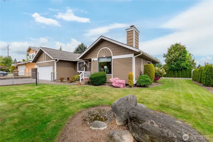 Meticulously maintained grounds featuring a unique rock focal point and a lush, wide side yard.
