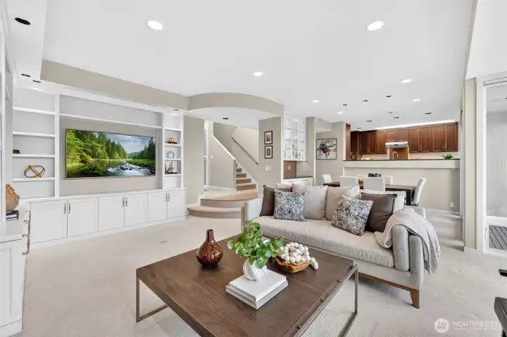The main level reveals the true scale of this home — a generously proportioned family room with custom built-ins, a curved archway opening to the staircase, and a direct sightline through to the kitchen and dining beyond. The open-plan layout connects living, dining, and cooking into one cohesive great room, giving every gathering a natural flow between spaces. New recessed lighting throughout and neutral finishes make this level as polished as the one above it.