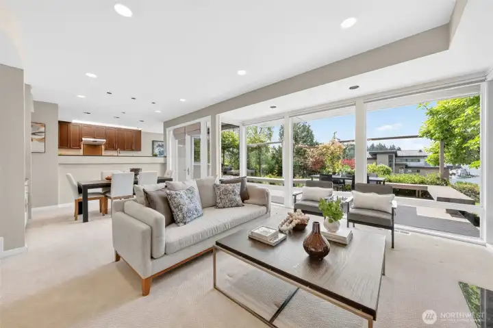 A wall of new casement windows frames Lake Washington and the Ohashi-designed garden in one uninterrupted panorama, with motorized Hunter Douglas blinds and sun shades ready to set the mood at the touch of a button. The open sightline through to the dining room and kitchen beyond makes this the effortless hub of daily life.