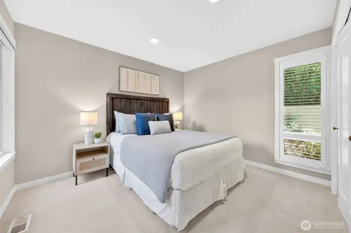 A calm, well-proportioned guest bedroom on the main level with new carpet, fresh neutral walls, and plantation-shuttered windows looking out to the mature garden. Quiet, private, and polished — equally suited for guests