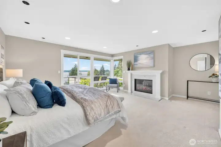 Wake up to Lake Washington every morning — the primary suite's corner windows and private deck access frame one of the best views in Lochleven, anchored by a gas log fireplace with marble surround that makes the room feel like a boutique hotel that never checks you out.