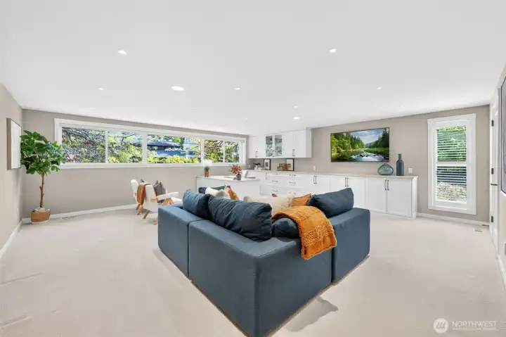 A sprawling family room that works as hard as it relaxes — custom white cabinetry spans the full wall with a generous built-in desk, glass-front uppers, and counter storage that makes this equally suited as a home office, homework hub, or media room.