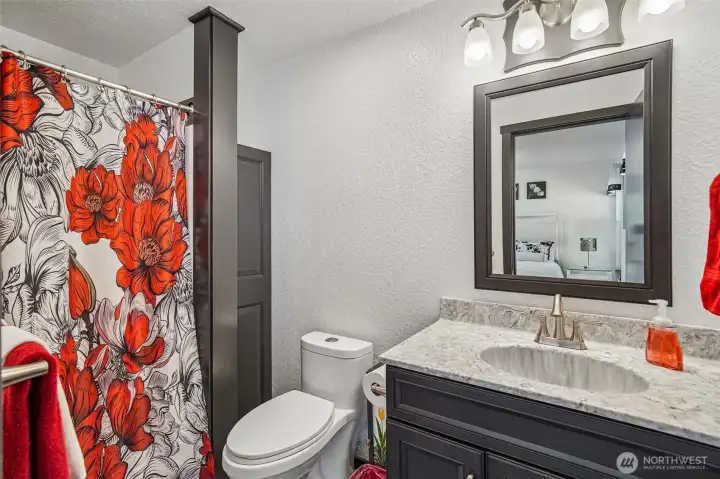 Full bath with quartz counters, tile floors, and storage