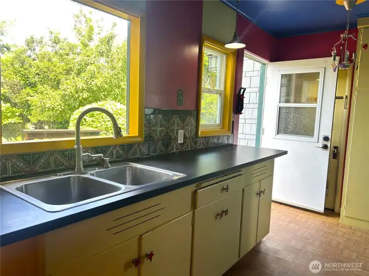 Entry through the back door to kitchen. Large windows overlooking the lovely backyard.