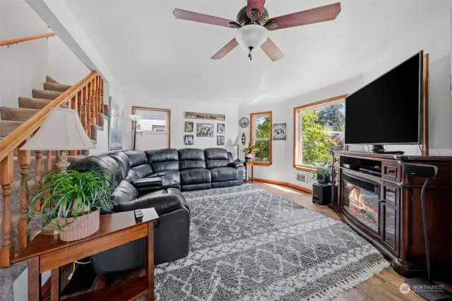 Family room with ceiling fan and large window providing an abundance of natural light.