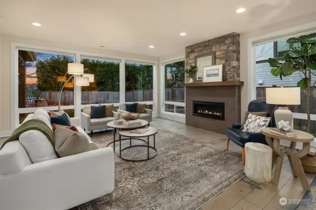 Spacious and sunlit family room with walls of windows and cozy gas fireplace