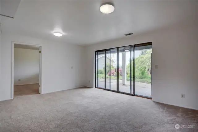 Family Room on the lower level with sliding glass doors out to the backyard and the patio. Also, doorway to 3rd Bedroom.