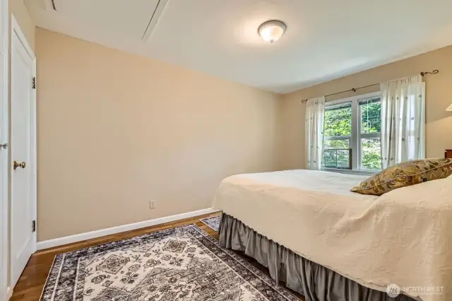 Main Floor bedroom (primary bedroom) with two closets. Both are cedar-lined. Gleaming hardwood floors and large windows add warmth and comfort. Tons of attic storage with access from this room, as well.