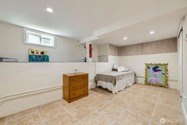 Downstairs bedroom (could be nonconforming). Tan panels lining the wall above the bed are cabinets that provide tons of storage for this room.