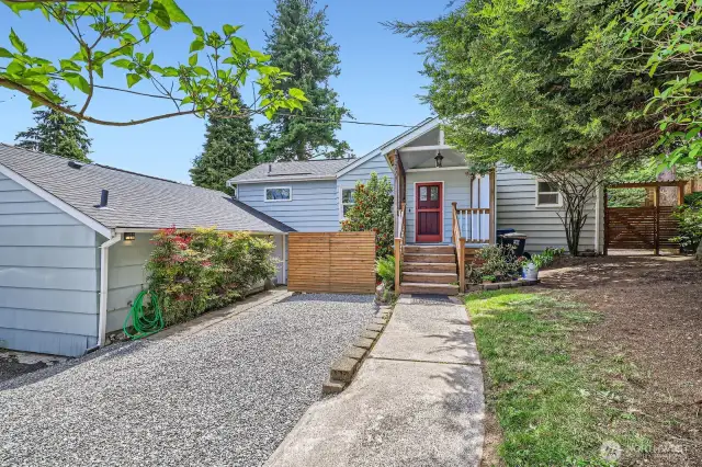 Wide shot of home shows gravel parking space. This home has plenty of parking for 4, and can accommodate an RV or boat. Behind the privacy screen on the left is the private patio belonging to the ADU.