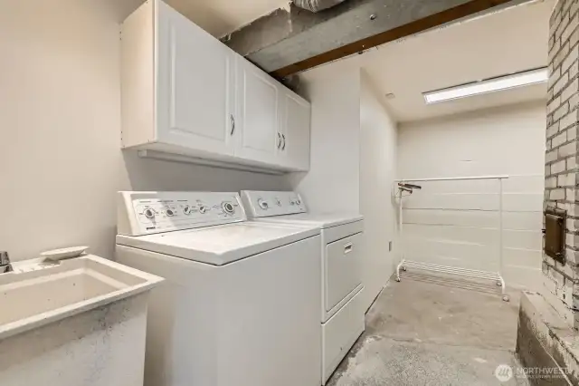 Large laundry room with sink and storage. Concrete floors.