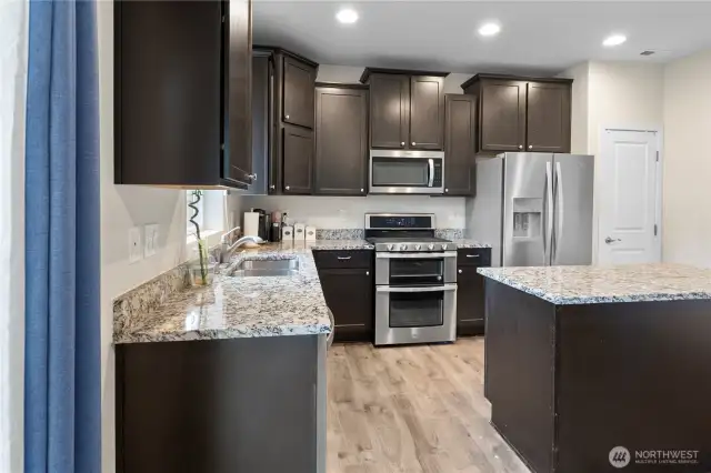 Stunning Dark brown cabinets, generous granite countertops and island!