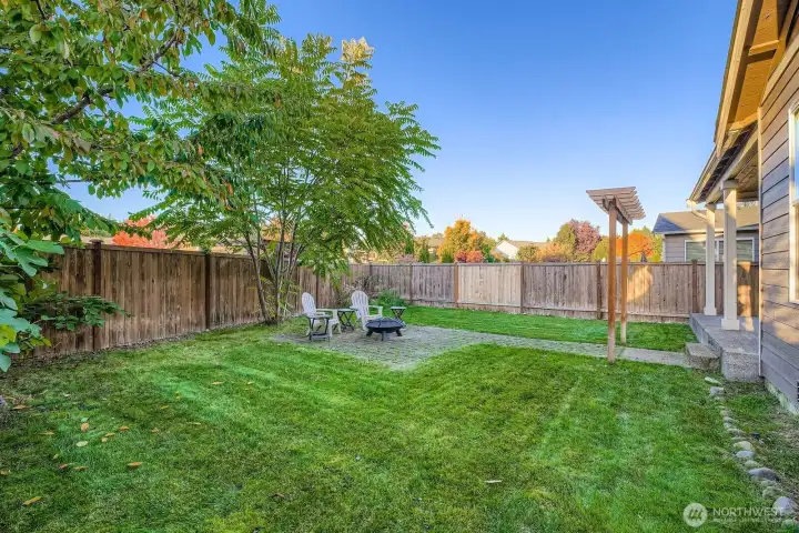 Spacious yard with a fire bowl set on brick pavers